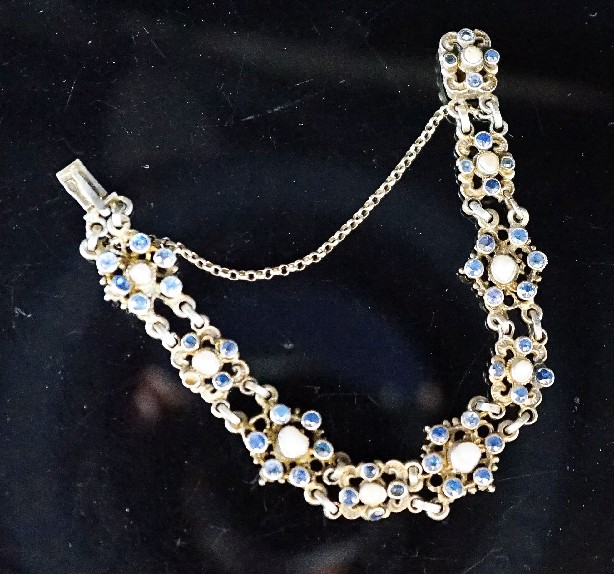 A continental gilt white metal, sapphire and split pearl flower head cluster set bracelet